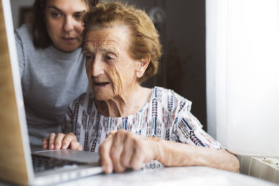 Granddaughter assisting grandmother while using laptop at home