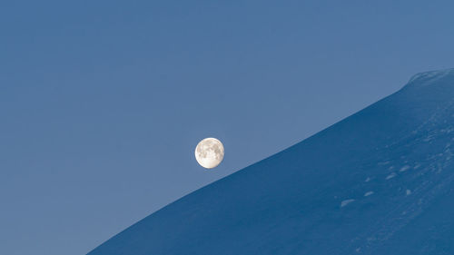 Low angle view of moon against clear blue sky