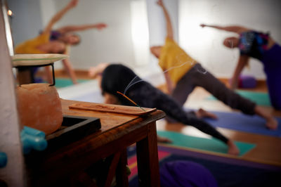 Close-up of incense burning on table against people exercising