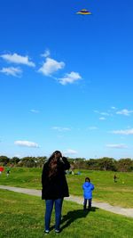 Rear view of women on field against sky