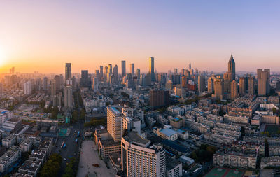 Aerial view of modern buildings in city against sky during sunset