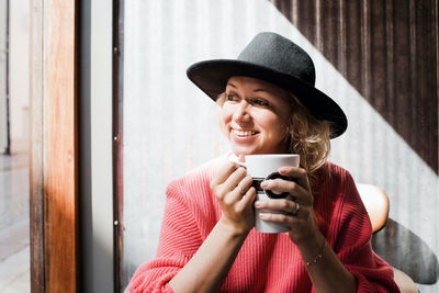 Portrait of a woman smiling whilst drinking coffee in a cafe