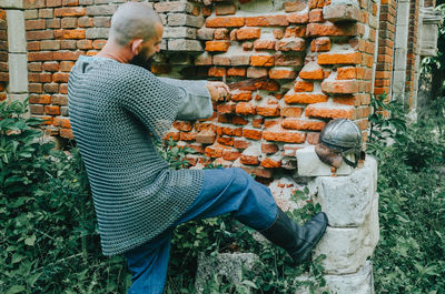 Viking warrior near an old brick castle . sword and helmet. rear view. person