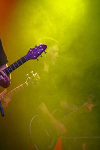 Side view of musician playing guitar seen through green smoke