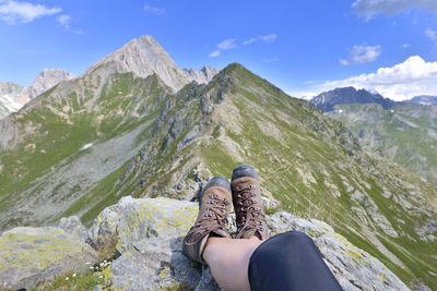 Low section of person on mountain against sky