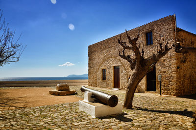 Old building by sea against blue sky