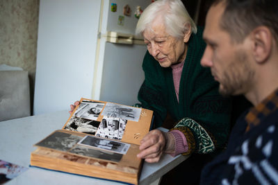 Grandmother and grandson are looking at an photograph album together.