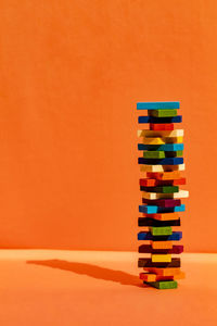 Stack of colored pencils on table against orange background