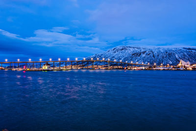 Scenic view of sea by snowcapped mountain against blue sky at night