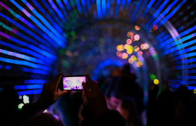 Close-up of hand holding illuminated lighting equipment at night