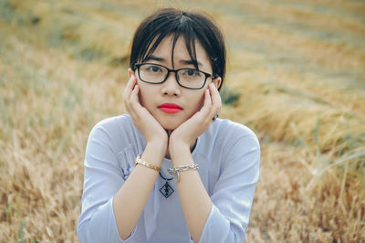 Portrait of serious young woman wearing eyeglasses on field