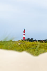 Lighthouse by sea against clear sky