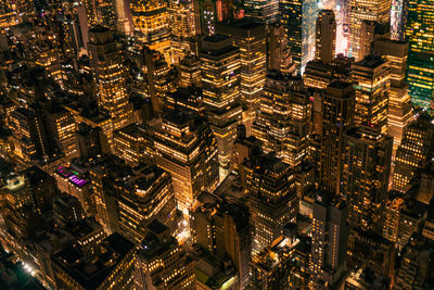 Aerial view of illuminated skyscraper buildings in city at night at high angle