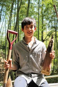 Full length of boy sitting on plant against trees