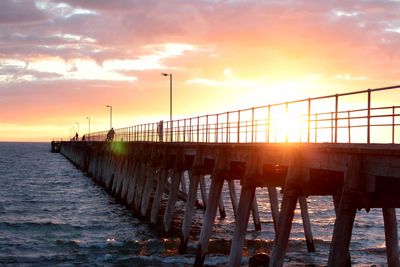 Pier over sea against sky during sunset