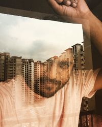 Digital composite image of man holding glass window against sky