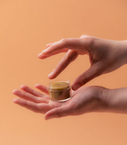 Midsection of person holding drink against orange background