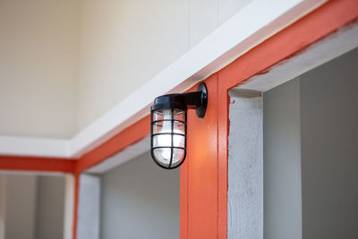 Close-up of electric lamp mounted on wall in building