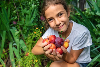 Portrait of cute girl holding plums