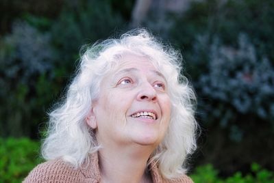 Portrait of a smiling gray-haired curly woman, look up.