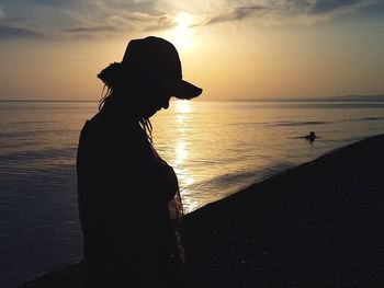 Silhouette woman standing at beach during sunset