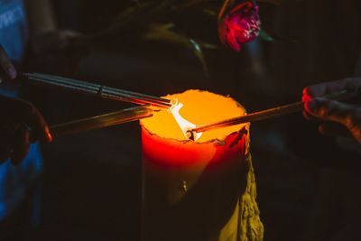 Cropped hands igniting sparklers with candle at night