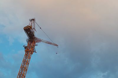 Low angle view of crane at construction site against sky