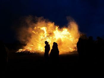 Silhouette people against fire at night