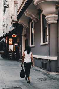 Full length rear view of woman walking on street in city