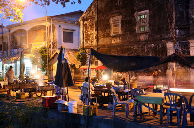 Illuminated market stalls on street at dusk