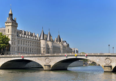 Bridge over river in city against clear sky