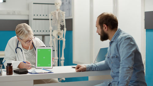 Doctor showing digital tablet to patient at clinic