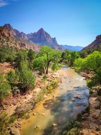 Scenic view of river and mountains against clear blue sky