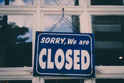 Close-up of closed text hanging outside store