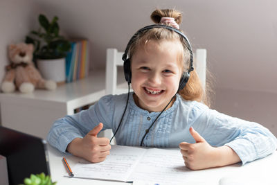 Distance learning courses online. happy cute girl sitting in headphones at a laptop at home