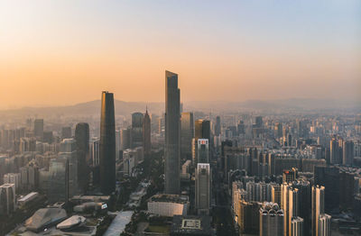 Aerial view of modern buildings in city against sky during sunset
