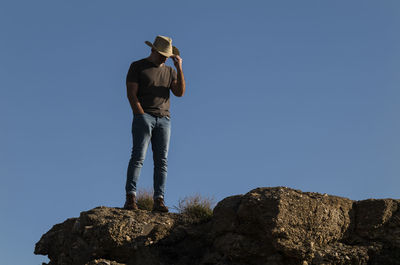 Adult man in cowboy hat standing on top of cliff in tabernas desert, almeria, spain