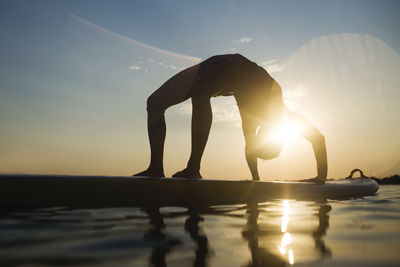 Silhouette man standing by sea against sky during sunset