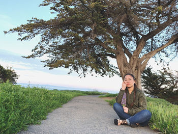 Portrait of woman sitting on field against trees