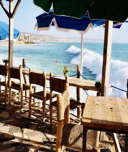 Chairs and tables at beach against sky