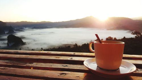 Close-up of coffee on table against sea during sunset