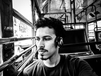 Young man looking through window while traveling in bus