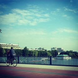 Man cycling on road against sky