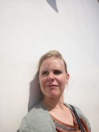 Portrait of beautiful young woman standing against wall