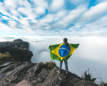 Rear view of woman standing on mountain against sky