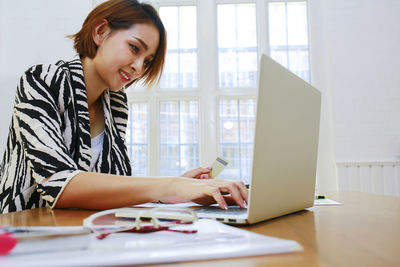Young woman using mobile phone while sitting on table