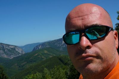 Portrait of man wearing sunglasses against mountains