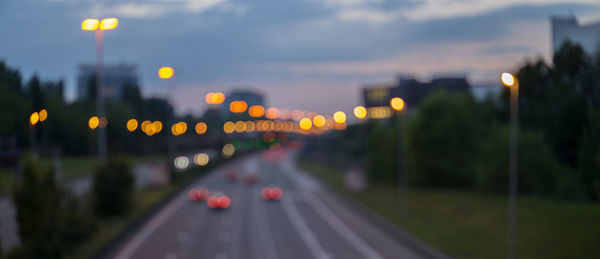 Defocused image of cars on highway against sky during sunset