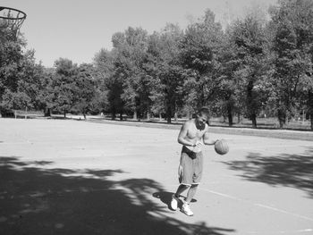 Full length of man practicing basketball at park