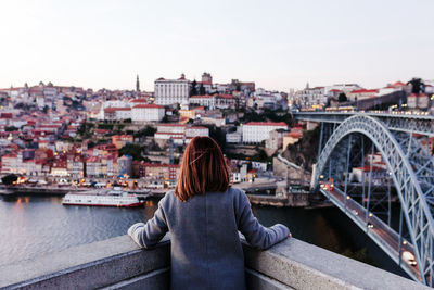 Back view of relaxed woman in porto bridge at sunset. tourism in city europe. travel and lifestyle